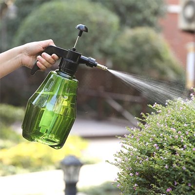 Pulverisateur vert arrose plante