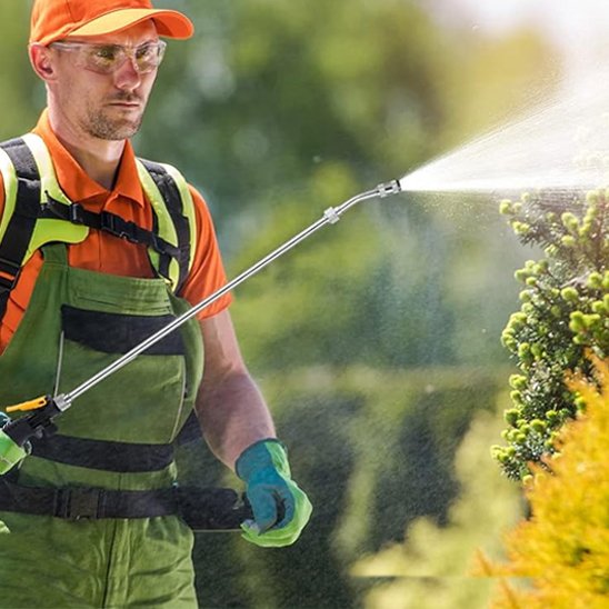 Technicien traite plantes avec lance pulverisateur 